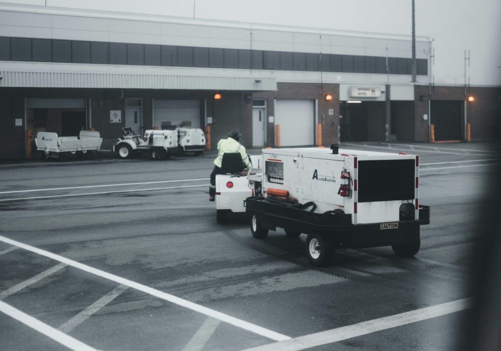 An airport vehicle towing equipment on a rainy day, highlighting airport operations and maintenance.